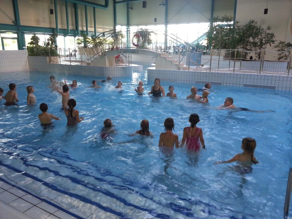 Die Schwimmausbildung und -training der DLRG Holmarksee e.V. findet im Campusbad in Flensburg statt. Auf dem Bild sieht man eine Gruppe Kinder im Anfängerschwimmbecken.